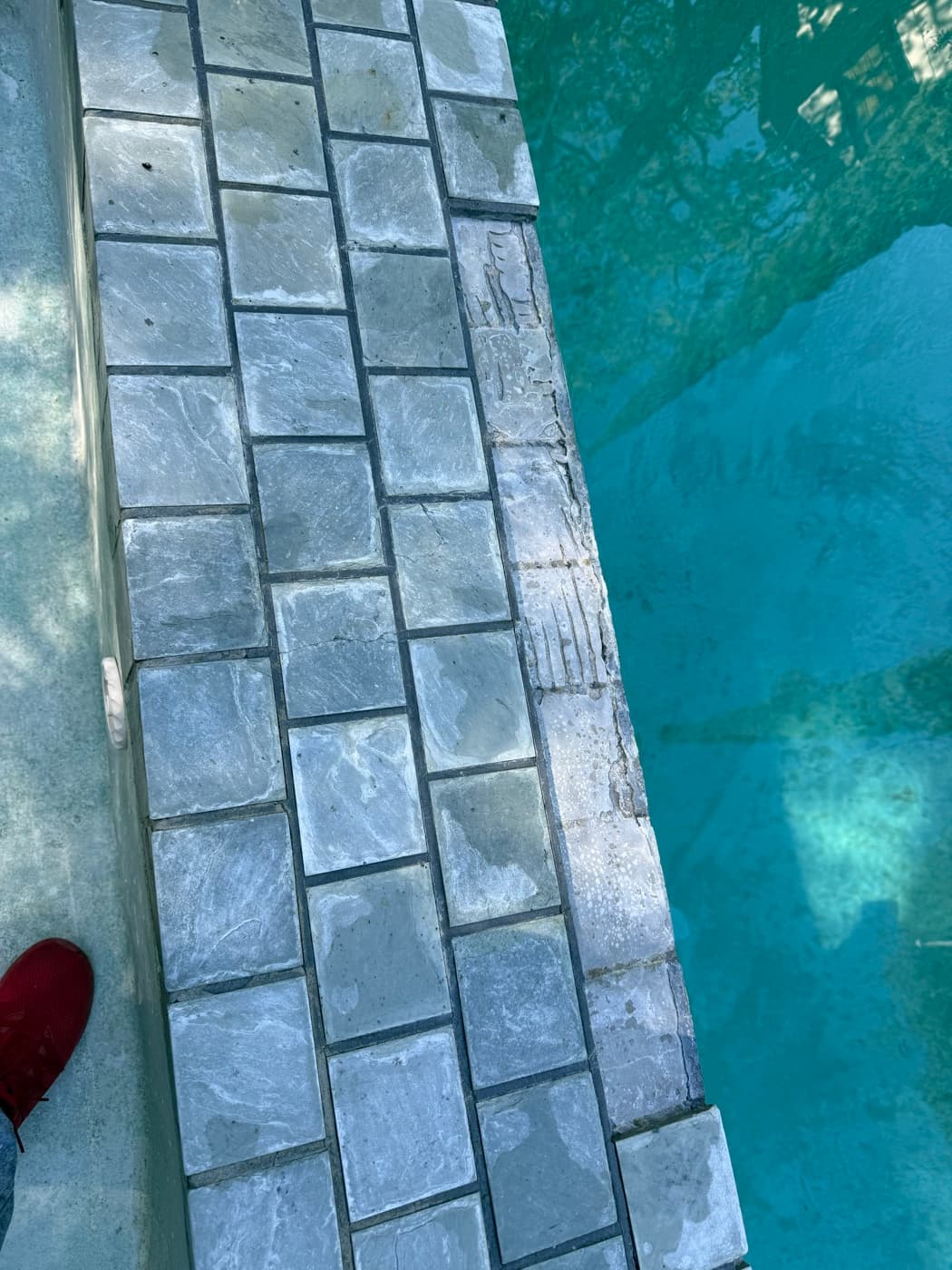 Pool coping stone tiles showing cracked grout before repair service by Sel Marin Pool Service