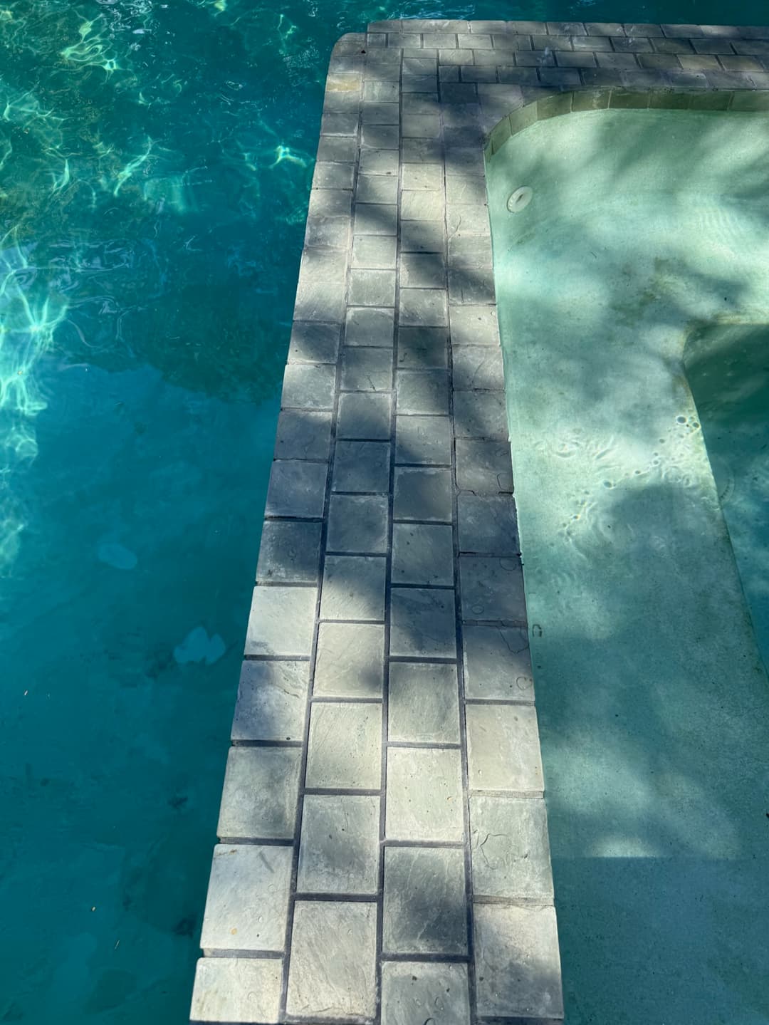 Stone-tiled pool and spa divider wall with clear turquoise water after professional pool service in Marin County CA