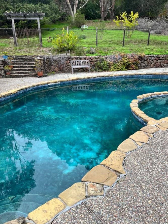 Clean residential swimming pool with stone coping after professional pool maintenance